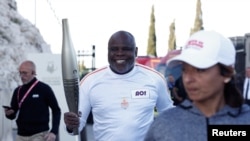 French former football player Basile Boli holds the Olympic torch during the relay ahead of the 2024 Paris Olympic Games, in Marseille, France, May 9, 2024.