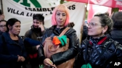 FILE - State workers Flavia, center, and Lia Pesaresi, right, protest the policies of President Javier Milei outside Congress, including the layoffs of some of their colleagues in Buenos Aires, Argentina, April 12, 2024.