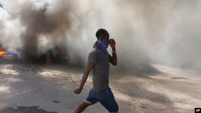 A man walks past burning tires set on fire by protesters to call attention to the country's insecurity and demanding the resignation of the prime minister, in Port-au-Prince, Haiti, Jan. 18, 2024.