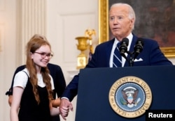 President Joe Biden holds the hand of Miriam Butorin, daughter of newly released Russian detainee Alsu Kurmasheva at the White House, Aug. 1, 2024. Biden asked people to sing "Happy Birthday" to the girl, who was celebrating her 13th birthday.