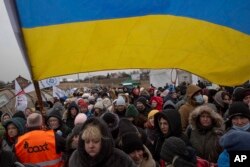 FILE - Sukarelawan Ukraina Oleksandr Osetynskyi (44 tahun), memegang bendera Ukraina dan mengarahkan ratusan pengungsi setelah melarikan diri dari Ukraina dan tiba di perbatasan di Medyka, Polandia, Senin, 7 Maret 2022. (AP/Visar Kryeziu, File)