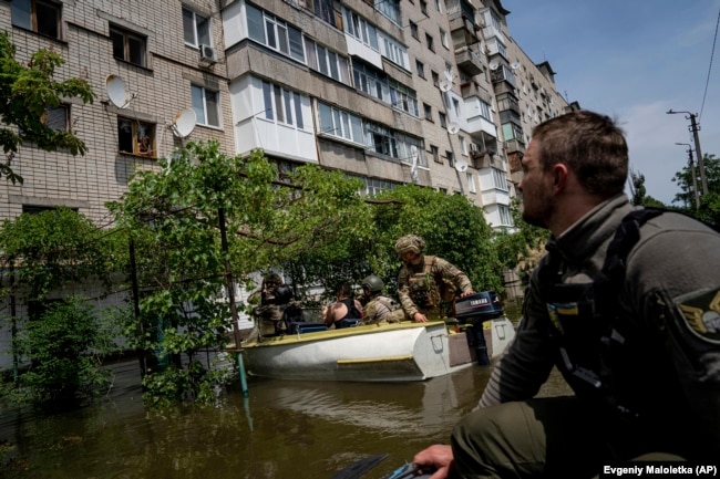 FILE - Ukrainian servicemen arrive by boats to evacuate people in a flooded neighborhood in Kherson, Ukraine, Thursday, June 8, 2023. (AP Photo/Evgeniy Maloletka)