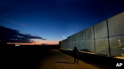 FILE - A man walks by the fence at the Pournara migrant reception center in Kokkinotrimithia outside of capital Nicosia, Cyprus, on Jan. 24, 2024.