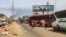 People wait next to passenger buses as smoke billows in an area in Khartoum where fighting continues between Sudan's army and paramilitary forces, April 28, 2023.