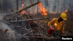 FILE - Kenyatta Bridges, 34, an inmate and member of Arcadia 20, sets fire to a burn pile during prescribed fire operations on a deployment near Northport, Washington, Oct. 25, 2023.