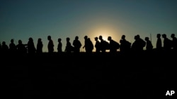 FILE - Migrants who crossed the Rio Grande and entered the US from Mexico line up for processing by U.S. Customs and Border Protection, Sept. 23, 2023, in Eagle Pass, Texas.