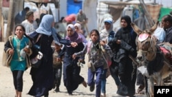 Palestinians rush during Israeli bombardment in an area of Rafah, June 19, 2024. The U.N. High Commissioner for Human Rights said it appeared Israel made no attempt to 'effectively distinguish' between Palestinian civilians and Hamas fighters in its bombing campaign of Gaza.