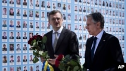 El Ministro de Asuntos Exteriores de Ucrania, Dmytro Kuleba, izquierda, y el secretario de Estado de EEUU, Antony Blinken, caminan con ramos de rosas rojas frente al Muro de la Memoria de los Defensores Caídos de Ucrania, en Kiev, el miércoles 15 de mayo de 2024. 