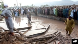 People gather to clear the rubble of a house partially damaged by landslide due to heavy rainfall in Surkhroad district of Jalalabad, Nangarhar province east of Kabul, Afghanistan, July 15, 2024.