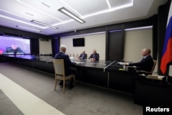 Russian President Vladimir Putin, right, and military officials, including Armed Forces leader Valery Gerasimov on screen, discuss the Ukrainian incursion into Russia, outside Moscow, Aug. 7, 2024. (Sputnik via Reuters)