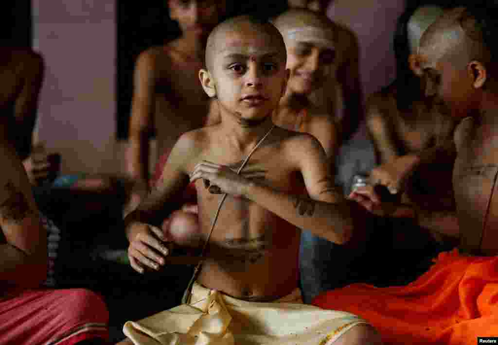 A novice Hindu priest applies cow dung on his body as part of a ritual performed to mark the Janai Purnima festival (Sacred Thread Festival) during which devotees take holy baths and change their sacred thread, also known as Janai, for protection and purification, at the premises of Pashupatinath Temple in Kathmandu, Nepal.&nbsp;