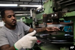 Seorang operator sedang memotong piringan hitam di pabrik Polysom, Belford Roxo, Brasil, Selasa, 16 April 2024. Tahun lalu, untuk pertama kalinya di Brasil, penjualan piringan hitam melampaui CD dan DVD. (Foto: AP)