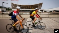 FILE - Cyclists ride near the Aquatic Center in Saint-Denis, north of Paris, July 10, 2023, in Paris.