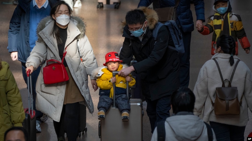北京西站，2023年1月18日，一位男士推着坐在手提箱上的孩子。中国人口出生率开始缓慢下降，使中国领导人面临新的考验。(photo:VOA)