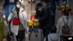 北京西站，2023年1月18日，一位男士推着坐在手提箱上的孩子。中国人口出生率开始缓慢下降，使中国领导人面临新的考验。