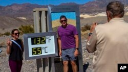 Tourists pose for a photo next to a thermometer displaying a temperature of 132 degrees Fahrenheit/55 degrees Celsius at the Furnace Creek Visitors Center, in Death Valley National Park, Calif., July 7, 2024. 