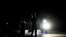 A woman with her son signals a car on a dark street during a blackout in Bauta municipality, Artemisa province, Cuba, on March 18, 2024. 