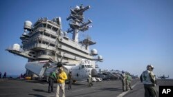 El personal de la cabina de vuelo pasa frente a los aviones a bordo del portaaviones USS GW Bush que navega en el mar Mediterráneo, el lunes 17 de octubre de 2022.