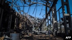 Locals examine the remains of an industrial building hit by a Russian missile, in Odesa, May 18, 2023, amid Russia's continued invasion of Ukraine.