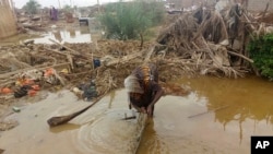 A woman sorts through floodwaters at her damaged home near Abu Hamdan, Sudan, on Aug. 7, 2024.