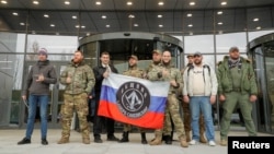FILE - Visitors pose outside PMC Wagner Center, which is a project implemented by the founder of the Wagner private military group, Yevgeny Prigozhin, during the official opening of the office block in Saint Petersburg, Russia, Nov. 4, 2022.
