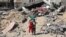A Palestinian child walks with a stuffed bear recovered from the rubble of a destroyed building following Israeli bombardment in Khan Yunis on June 21, 2024.
