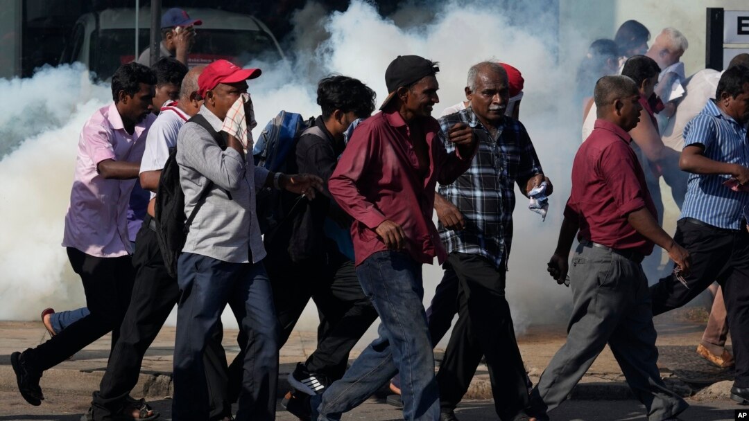 Opposition party members run for cover from police firing tear gas during a protest rally in Colombo, Sri Lanka, Feb. 26, 2023.