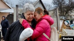 সাম্প্রতিক গোলাগুলিতে আহত স্থানীয় বাসিন্দা সভেতলানা বোইকোকে ডনেটস্কে তাদের ধ্বংসপ্রাপ্ত বাড়ির কাছে দাঁড়িয়ে ইউলিয়া ক্রিউকোভা সান্ত্বনা দিচ্ছেন। ১২ মার্চ, ২০২৩।