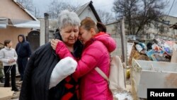 Svetlana Boiko, que foi ferida num ataque recente, é consolada por sua conhecida Yulia Kryukova, perto da sua casa destruída, em Donetsk, Ucrânia, a 12 de Março de 2023.