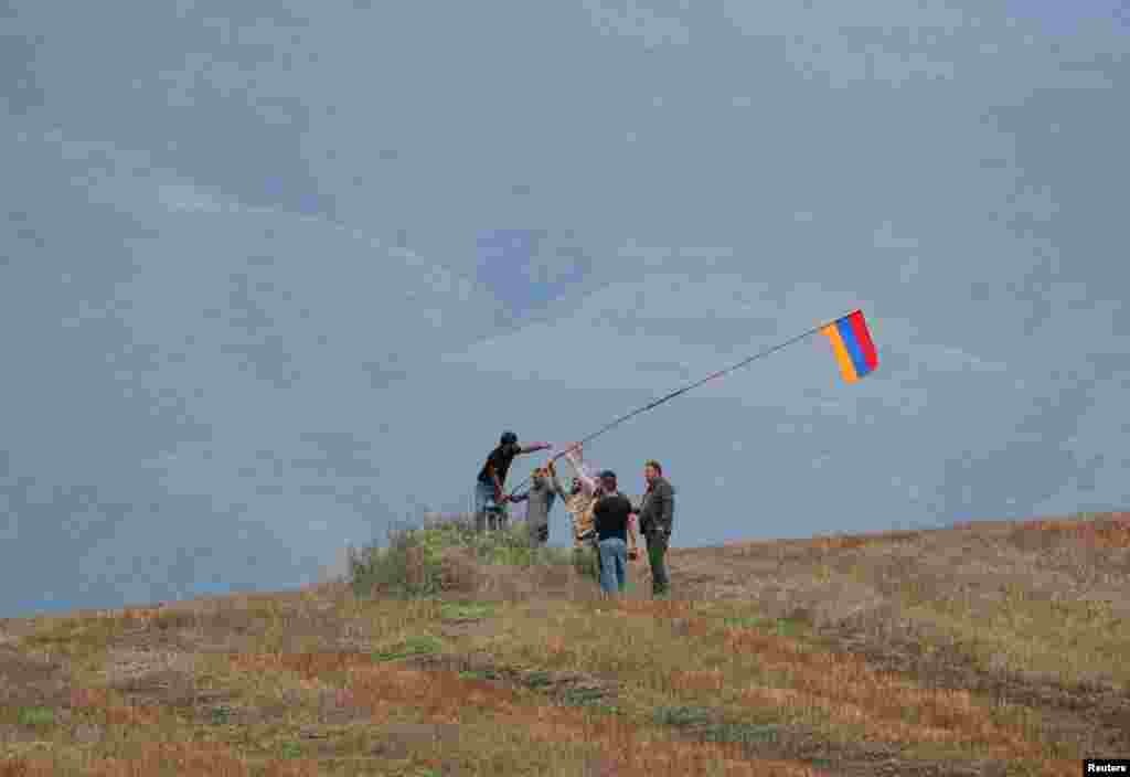 Men install an Armenian flag next to a checkpoint on the road leading to Azerbaijan&#39;s Nagorno-Karabakh region, near the village of Kornidzor, Armenia. REUTERS/Irakli Gedenidze