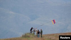 Men install an Armenian flag next to a checkpoint on the road leading to Azerbaijan&#39;s Nagorno-Karabakh region, near the village of Kornidzor, Armenia. REUTERS/Irakli Gedenidze