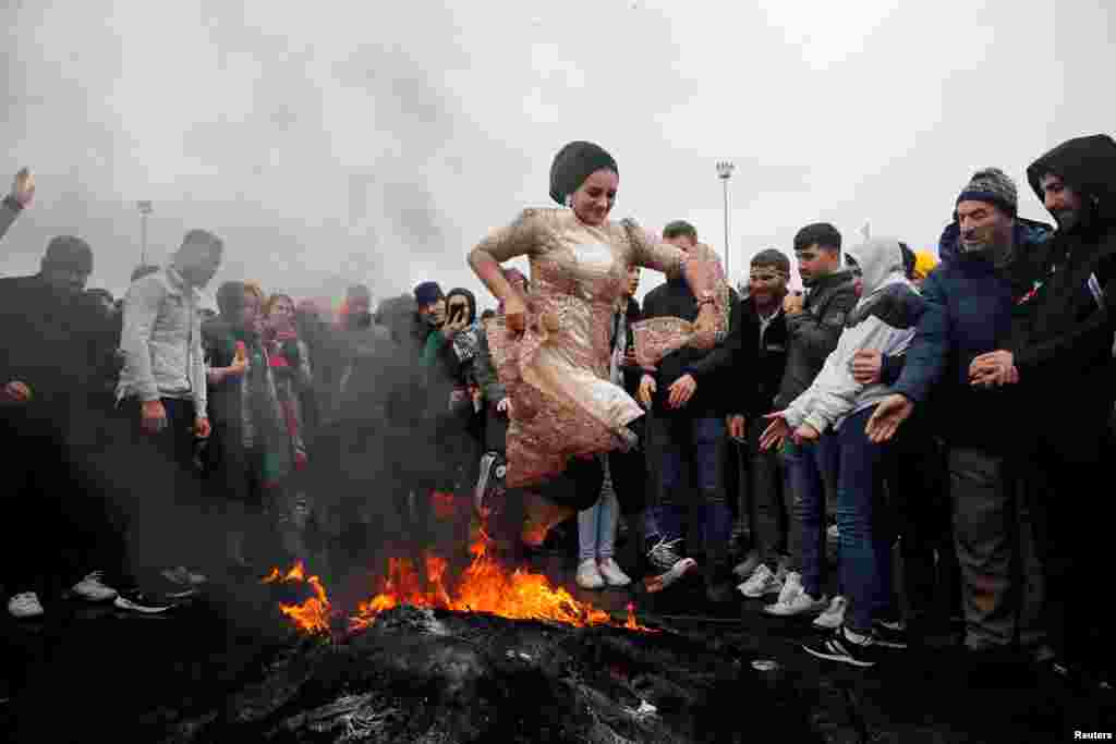 Жена скока преку огнот за време на настан за прослава на Новруз, кој го означува доаѓањето на пролетта, во Истанбул, Турција, 19 март 2023 година.