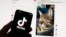 FILE - The TikTok logo is seen on a mobile phone in front of a computer screen which displays the TikTok home screen, in Boston, March 18, 2023.