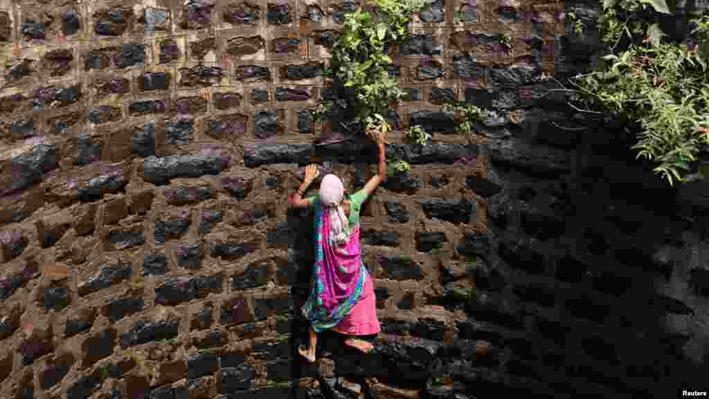 Suman Bhutambare attempts to climb up a well after retrieving a friend&#39;s sieve that fell into the well, in Telamwadi near Mumbai, India.