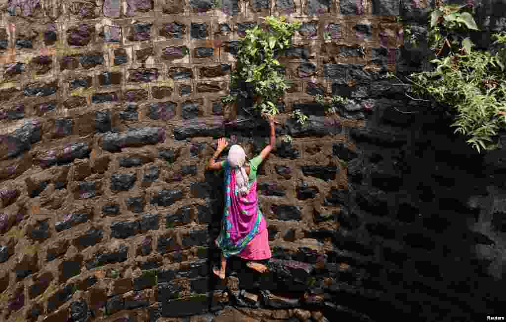 Суман Бутамбаре се обидува да се искачи од бунар, во Теламвади во близина на Мумбаи, Индија.