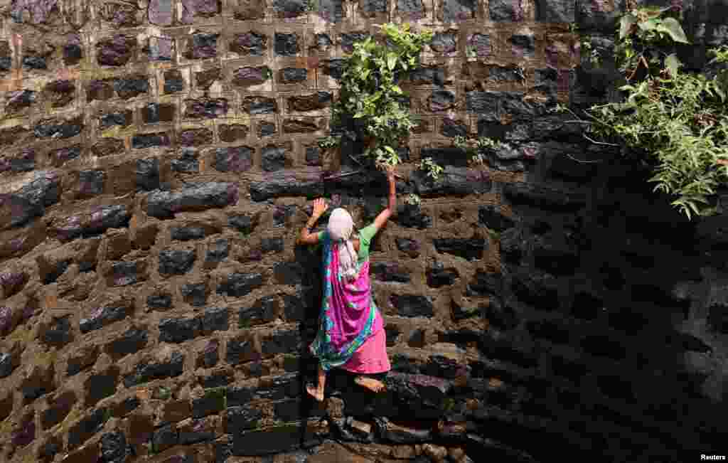 Suman Bhutambare attempts to climb up a well after retrieving a friend&#39;s sieve that fell into the well, in Telamwadi near Mumbai, India.