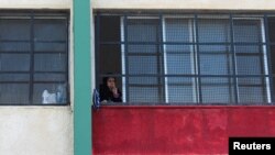 FILE - A woman looks out from school turned to a shelter for families affected by the deadly earthquake, in Latakia, Syria, Feb. 23, 2023. Classes resumed in Syrian schools on Feb. 25, 2023, but many children fear for their safety inside their school buildings.
