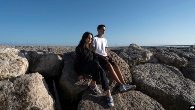Siblings Sofia Oliveira, 18, and Andre Oliveira, 15, pose for a picture at the beach in Costa da Caparica, south of Lisbon, Sept. 20, 2023.