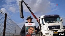 Varda Ben Baruch posa con una foto de su nieto junto al camión con los altavoces por los que las familias de los secuestrados les hablaron hoy desde la frontera con Gaza.