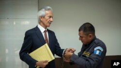 Seorang petugas tampak melepas borgol dari tangan jurnalis Jose Ruben Zamora ketika ia tiba di pengadilan untuk persidangan kasus tuduhan pencucian uang yang membelitnya di Guatemala City, pada 2 Mei 2023. (Foto: AP/Santiago Billy)