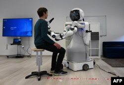 An employee sits in front of the robot Garmi in the laboratory of the Research Center Geriatronics of the Technical University Munich, in Garmisch-Partenkirchen, March 6, 2023.