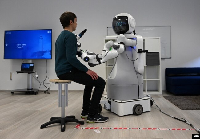 An employee sits in front of the robot Garmi in the laboratory of the Research Center Geriatronics of the Technical University Munich, in Garmisch-Partenkirchen, March 6, 2023.