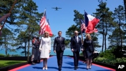 U.S. President Joe Biden walks with U.S. first lady Jill Biden, right, French President Emmanuel Macron, second from left, and his wife, Brigitte Macron, during ceremonies to mark the 80th anniversary of D-Day in Normandy, June 6, 2024. 