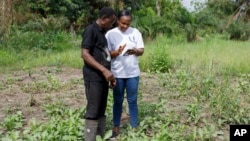 Rita Quansah, right, from Uniti Networks, shows farmer Cyril Fianyo how to navigate the farmers' apps on his phone in Atabu, Hohoe, in Ghana's Volta Region, April 18, 2024.