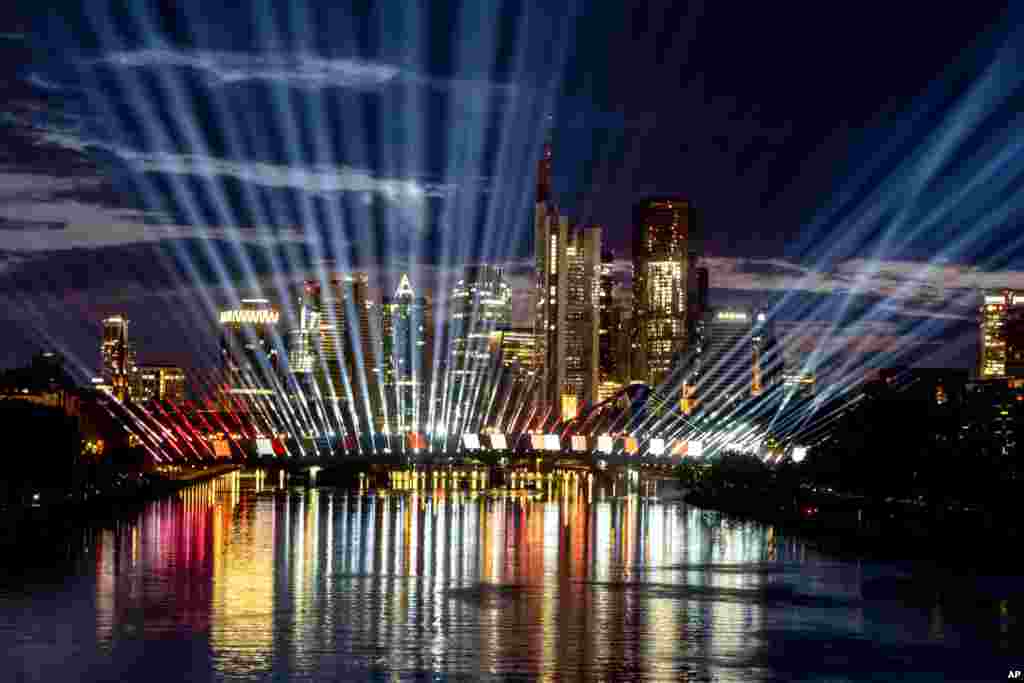 A test run of a light show illuminates the sky and the river Main in Frankfurt, Germany, June 11, 2024. 