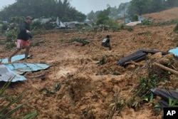 Warga meninjau lokasi longsor yang melanda sebuah desa di Pulau Serasan, Kabupaten Natuna, Senin, 6 Maret 2023. (BNPB via AP)