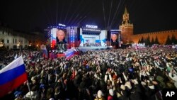 Prezidan Ris Vladimir Putin paret sou ekran televizyon yo sou Plas Wouj Moskou a pou selebre viktwa elektoral li, 18 Mas, 2024. 