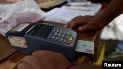 Un vendedor procesa un pago en un punto de venta en un mercado de Caracas el 10 de febrero de 2023. REUTERS/Gaby Oraa