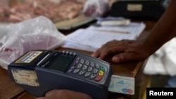 Un vendedor utiliza un dispositivo de punto de venta (POS) en un mercado de frutas y verduras al aire libre en Caracas, Venezuela, 10 de febrero de 2023.