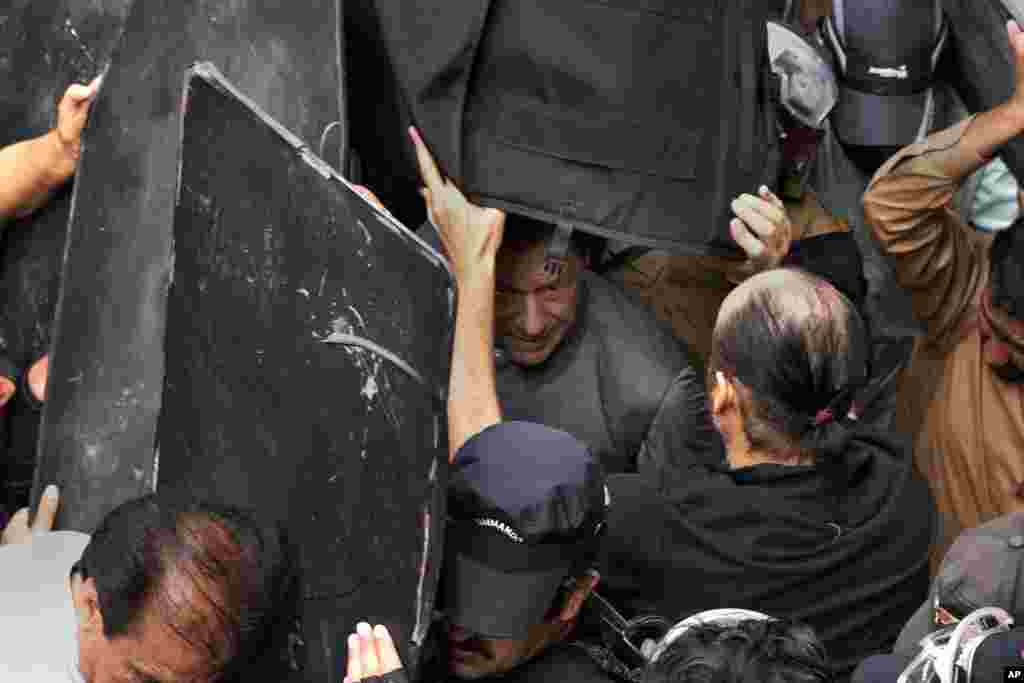 Security personnel hold bulletproof shields to secure former Prime Minister Imran Khan, center, after appearing in a court, in Lahore, Pakistan.